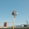 A convex mirror reflects buildings under a blue sky.