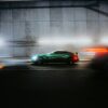 A green car drives through a dark tunnel.
