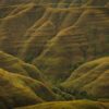 Rolling hills covered in grass and shadow.