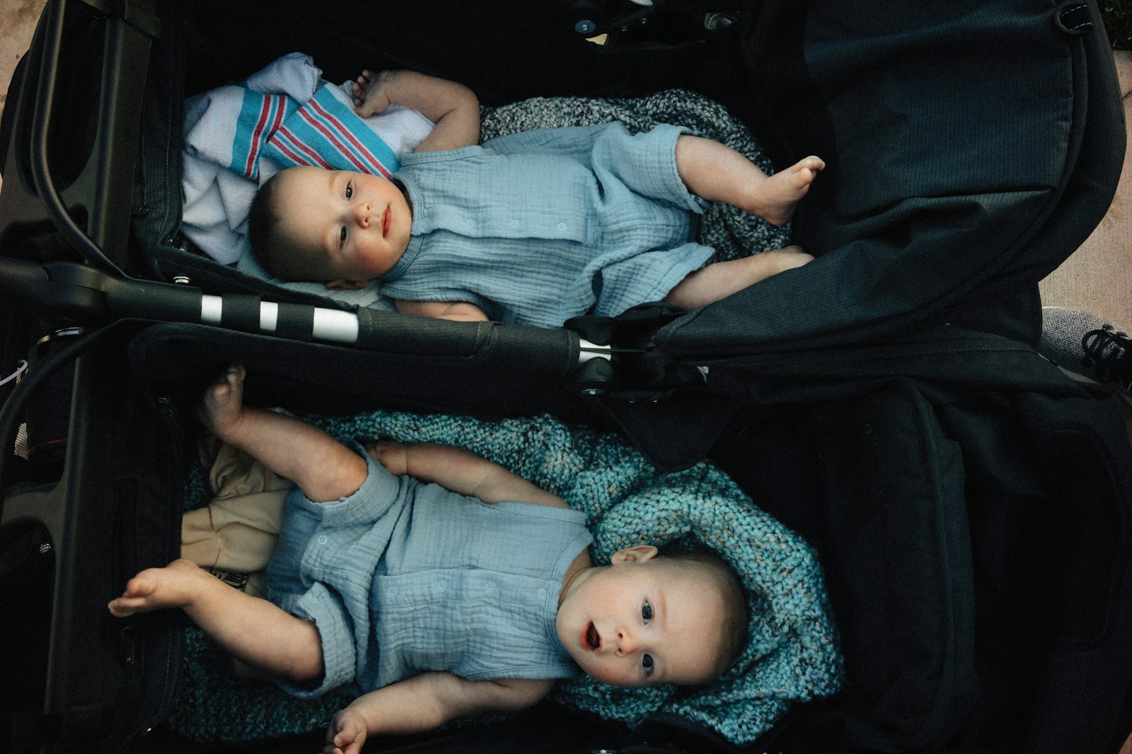 Two babies are resting in a stroller.