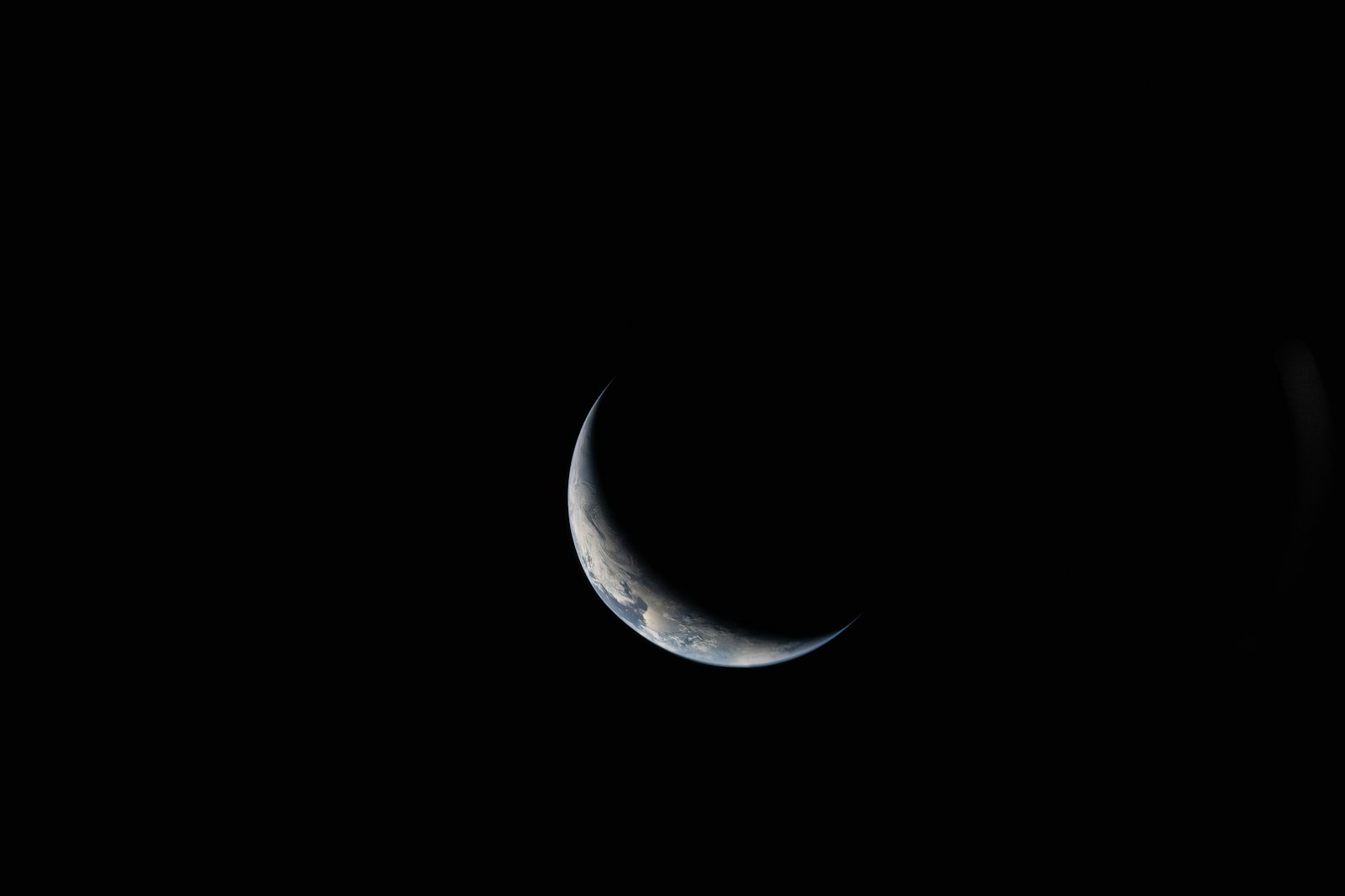 Crescent earth visible in the dark expanse of space