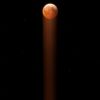 Blood moon in starry night sky with light beam