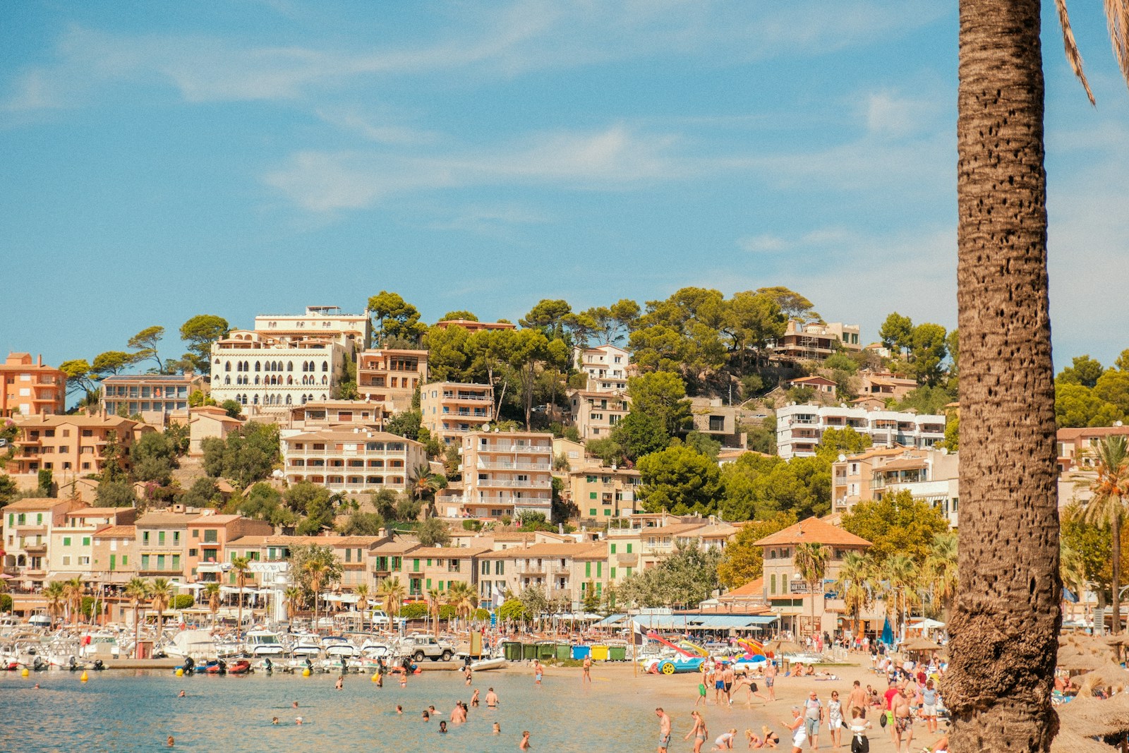 Coastal town with buildings on a hill overlooking beach.