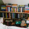 Bookshelves filled with books and stacked on the floor.