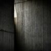 Light streams through a vertical gap in dark concrete.