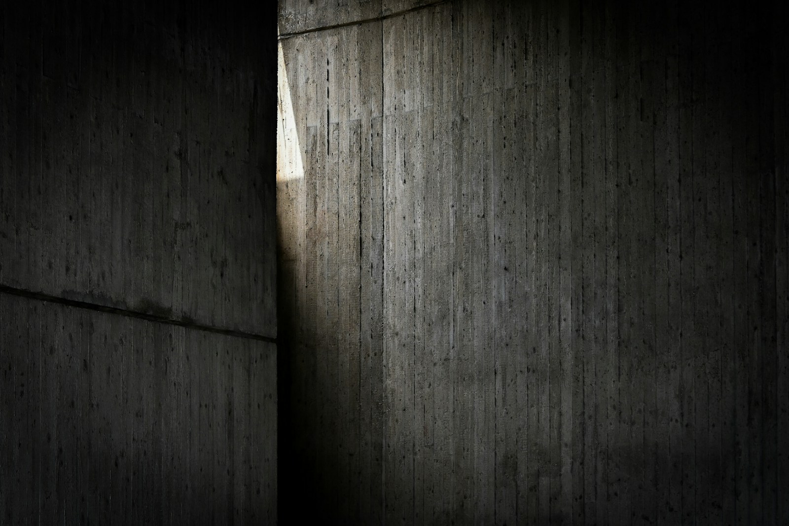 Light streams through a vertical gap in dark concrete.