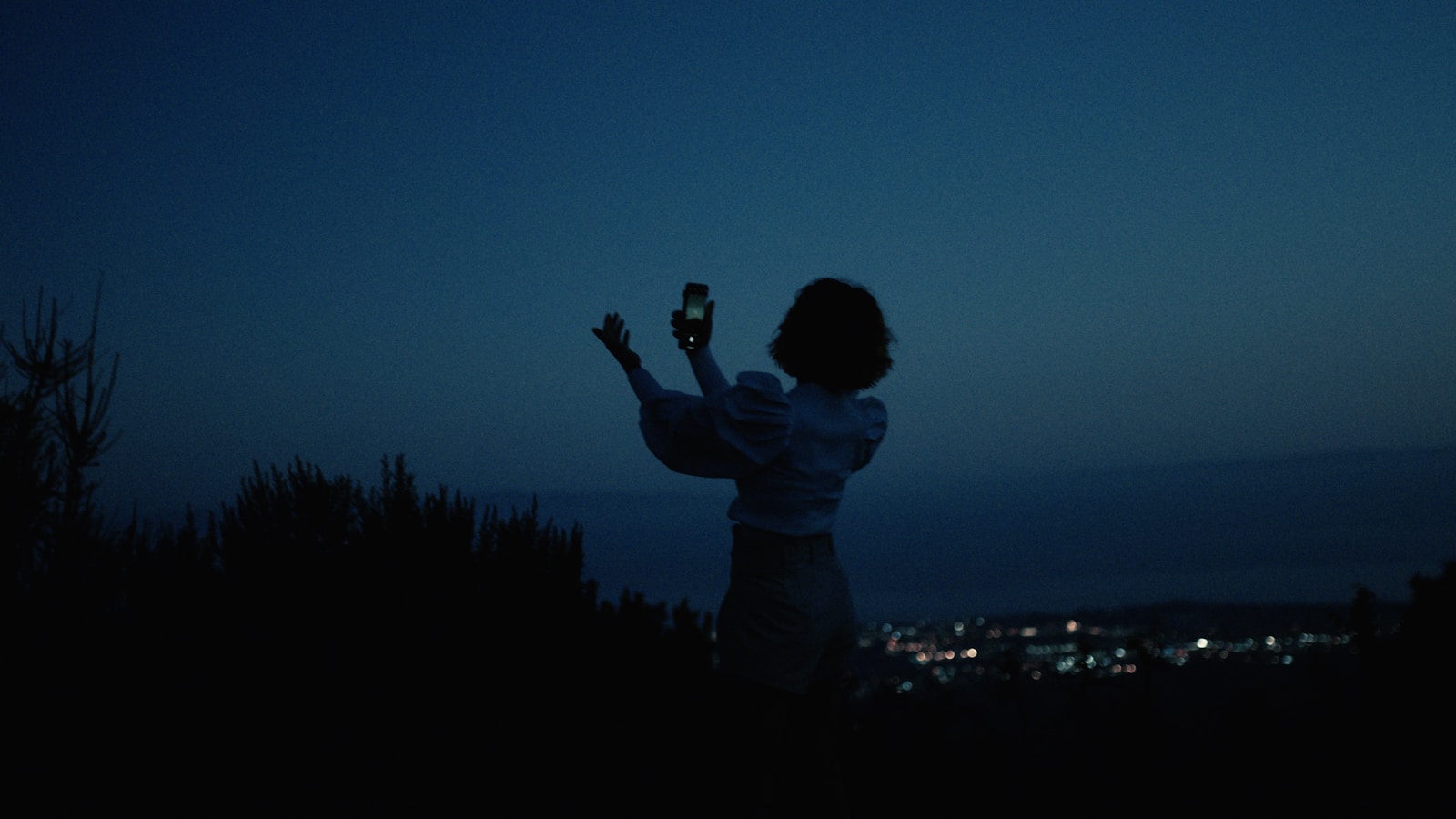 Woman taking a selfie with a phone at night.